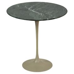 an oval table with a marble top and metal base, against a white background or backdrop