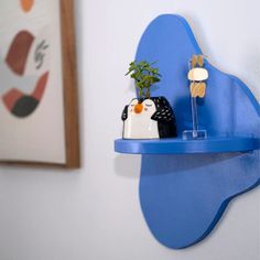 a blue shelf with two figurines and a potted plant sitting on it