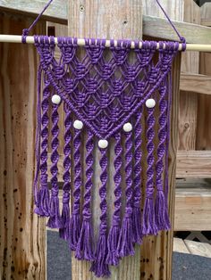 a purple macrame hanging from a wooden post