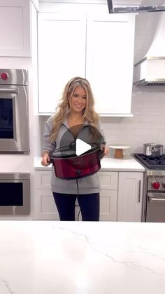 a woman standing in a kitchen holding an oven mitt