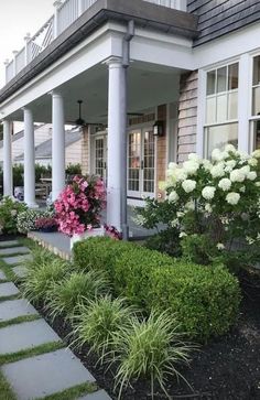 an image of a front yard with flowers and plants on the side of the house