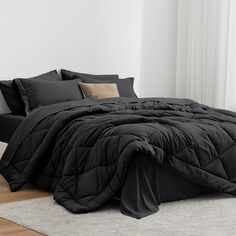 a bed with black comforter and pillows on it