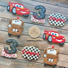 decorated cookies with cars and numbers are on a wooden table, ready to be eaten