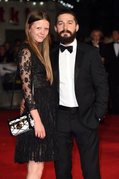 a man in a tuxedo standing next to a woman on a red carpet