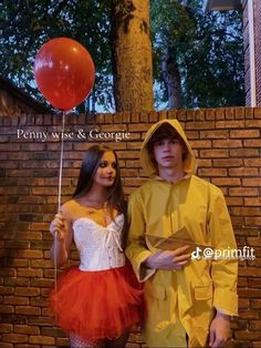 two people dressed in costumes standing next to each other and one holding a red balloon