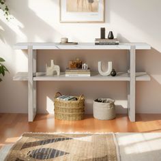 a white shelf with books and other items on it in a living room next to a potted plant