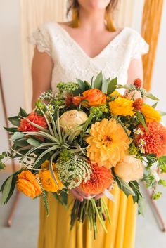 a woman holding a bouquet of orange and yellow flowers