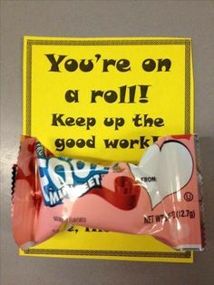 a candy bar wrapped in pink and white wrapper next to a yellow sign that says, you're on a roll keep up the good work