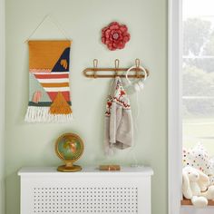 there is a coat rack on the wall with two scarves and a teddy bear next to it