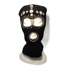 a black mask with jewels and pearls on the eyes is shown against a white background