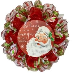 a red and green christmas wreath with santa claus on it's face, saying believe in the magic of christmas