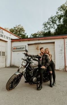 a man and woman sitting on a motorcycle in front of a storage area with garage doors