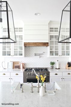 a kitchen with two hanging lights over the stove and counter top, along with white cabinets