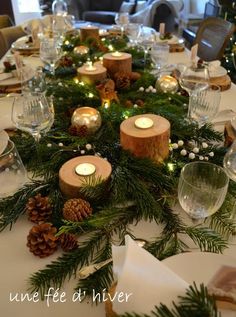 the table is set with candles, pine cones and evergreen branches for christmas dinner party