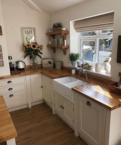 a kitchen with white cabinets and wooden counter tops, sunflowers on the window sill