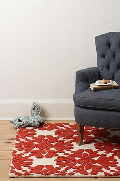 a blue chair sitting on top of a wooden floor next to a red and white rug