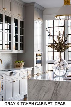 a kitchen with white cabinets and marble counter tops, gold accents on the doors and windows