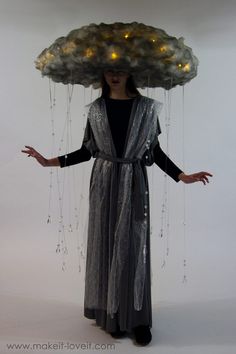 a woman wearing a large cloud hat with lights hanging from it's sides and her hands out