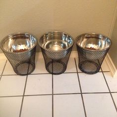 three metal bowls sitting on top of a tiled floor