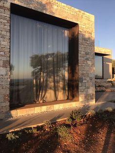 the reflection of trees in the window of a house with stone walls and windowsills