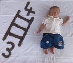 a baby laying on top of a white blanket next to a sign that says hello