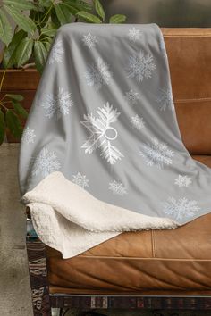 a couch covered in a blanket with snowflakes on it next to a potted plant