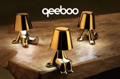 three gold colored lamps sitting on top of a wooden table next to a sign that says peebo