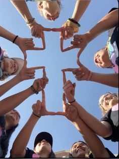 a group of people standing in a circle holding their hands together and making the shape of a heart