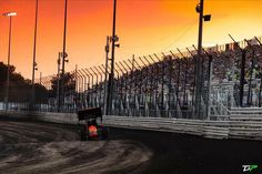 a dirt bike racing track with the sun setting in the background and many spectators watching