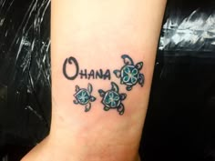 a small tattoo on the wrist that says ohana with three turtles and an o