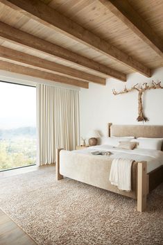 a bedroom with a large bed and wooden beams on the ceiling, along with an open window