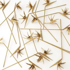 gold sticks and spikes are arranged on a white surface, forming an abstract pattern that looks like it has been made out of metal