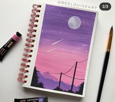 a notebook with an image of the moon and stars on it next to some markers