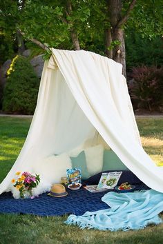 a white tent sitting on top of a blue rug in the middle of a field