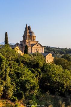 an old church on top of a hill surrounded by trees