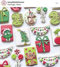 many decorated cookies are displayed on a white surface with green and red decorations around them