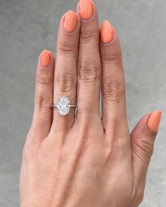 a woman's hand with an orange manicured nail polish holding a diamond ring