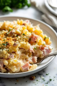 a white plate topped with macaroni and cheese covered in toppings next to a fork