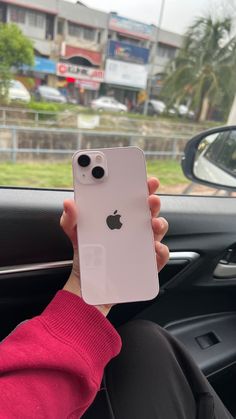 a person holding an iphone in their hand while sitting in the driver's seat