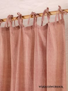 pink curtains hanging on a wooden rod in front of a white wall with the word warthwonder written below it