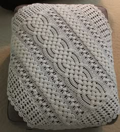 a white crocheted blanket sitting on top of a pillow