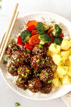 a white plate topped with meatballs and veggies next to chopsticks