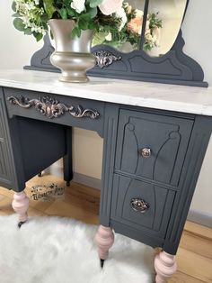 a desk with a mirror and flowers on it in front of a white fur rug