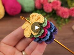 a crocheted flower being held by someone's hand