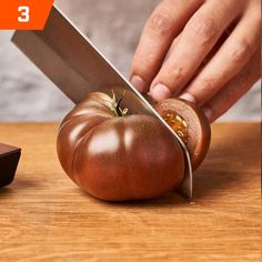 a person is cutting up a tomato with a knife on a wooden table next to a mouse