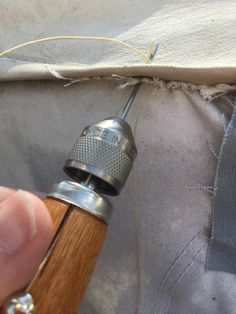 someone is using a small tool to thread together fabric