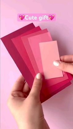 a person holding up pink cards with hearts on the back and one hand reaching for them