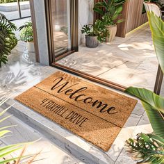 a welcome mat sitting on the ground in front of a building with potted plants