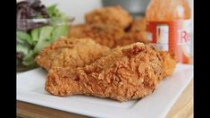 fried chicken on a white plate next to salad