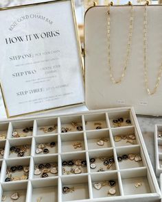 an open white box with jewelry in it sitting on a table next to other boxes